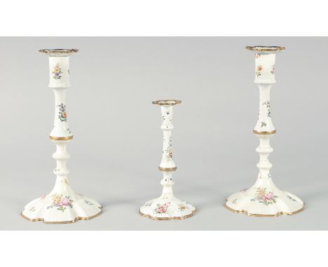 A PAIR OF BILSTON ENAMEL CANDLESTICKS painted with flowers. 9.5ins high and another smaller, 6.5ins high. (3).