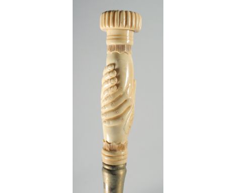 A CARVED BONE CLASPED HAND HANDLED WALKING STICK.