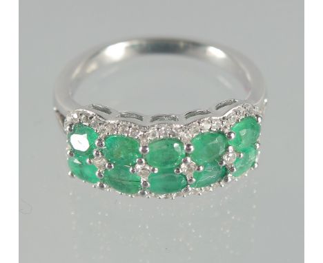 A SILVER AND EMERALD DOUBLE ROW RING.