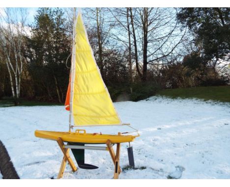 R/C Boats - Yellow fibreglass sailing boat, appears to have a battery operated rudder with a wooden stand, approximately 52 c