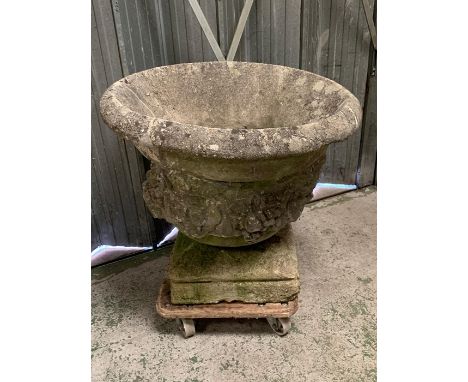 A large stone planter with cherubs to sides and square base