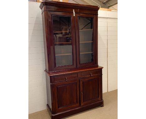 A mahogany bookcase with two glazed doors enclosing adjustable shelves, the base with a square edged top over two arched pane