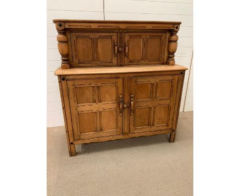 A light oak sideboard with cupboard top and bottom and turned decorative pillars to side. (H124cm W120cm xD45 cm)