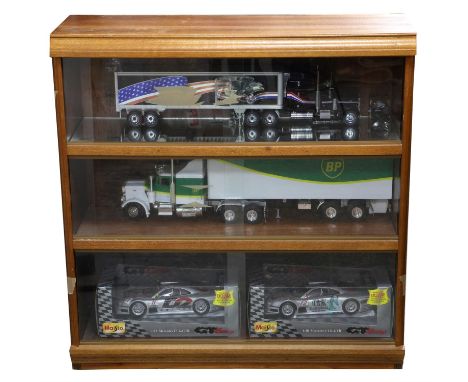 Four models in a glass display cabinet - includes one large BP truck, one American style black struck with eagle design & two