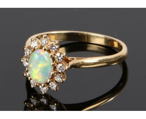 18 carat opal and diamond ring, with an oval cabochon cut opal and diamond surround, ring size P