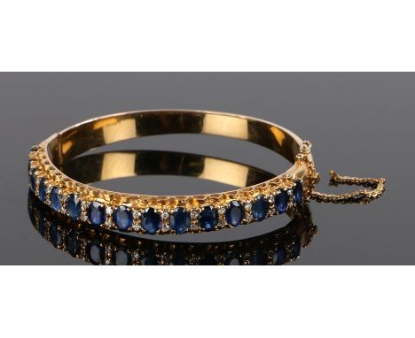 Sapphire set bracelet, with a row of sapphires set to the yellow metal bangle, 62mm diameter 