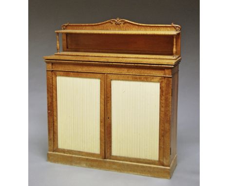 A William IV burr satinwood chiffonier, the superstructure with shelf and scrolling support, above two doors inset with pleat