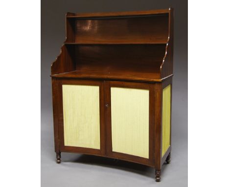 A Regency mahogany chiffonier, circa 1810, of concave form with two shelf back over a base with pleated silk doors and side p