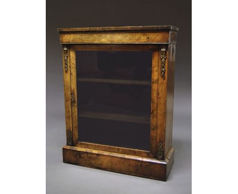 A Victorian walnut display cabinet, decorated with gilt metal, with glazed door opening to reveal three shelves, on a plinth 