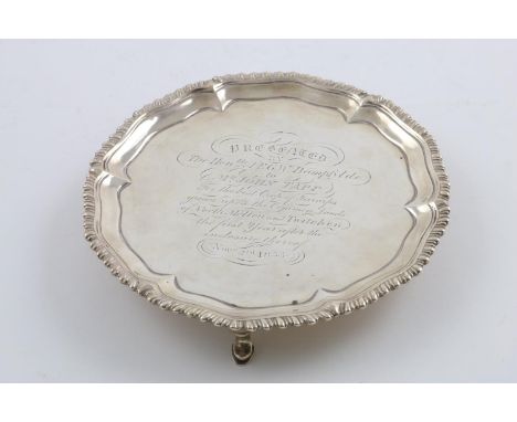 A GEORGE III SMALL SALVER. of shaped circular outline, with a gadrooned border and three hoof feet, inscribed, by Ebenezer Co