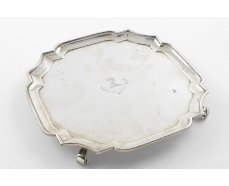 A GEORGE V SALVER. of shaped square outline, with a moulded border and resting on four scroll feet, crested, by Goldsmiths &a