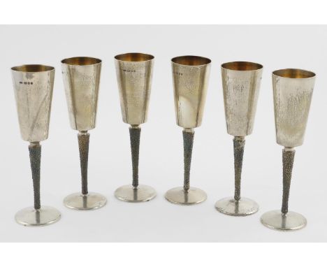BY STUART DEVLIN:-. A set of six Elizabeth II parcel-gilt champagne goblets with textured stems and a hammered finish, London