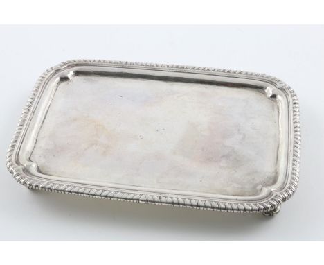 A GEORGE III TRAY. of rounded rectangular form, with a gadrooned border, incurved corners and four scroll feet, by John Parke