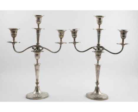 A PAIR OF EDWARDIAN THREE-LIGHT CANDELABRA. of tapering fluted form, with two scrolling arms, each supporting an urn finial, 