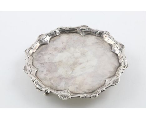 A GEORGE III SMALL SALVER OR WAITER. of shaped circular outline, with a husk and scroll border and resting on three hoof feet