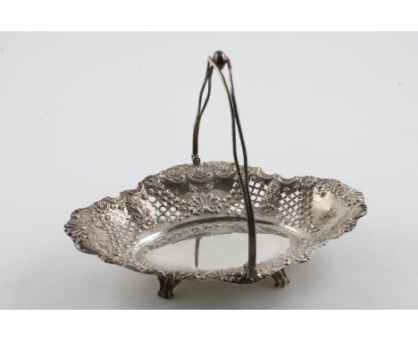 A LATE VICTORIAN CAKE BASKET. of shaped oval outline, with a swing handle, the body with pierced sides and embossed with flow