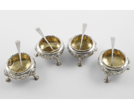 A SET OF FOUR VICTORIAN SQUAT CIRCULAR SALTS. on three mask and shell feet, with embossed floral decoration on the sides, cre