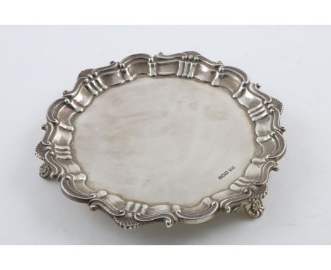 A GEORGE V SALVER. of shaped circular outline, with a husk and scroll border, on three legs, by Walker &amp; Hall, Sheffield 