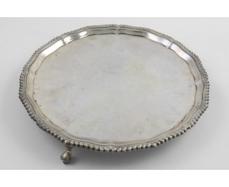 A LATE VICTORIAN SALVER. of shaped circular outline, with a gadrooned border and supported on three ball and claw feet, by R 