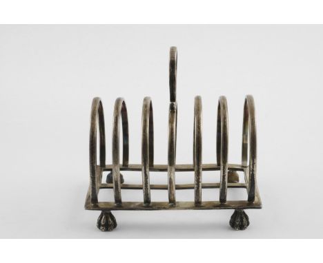 A GEORGE V LARGE TOAST RACK. with seven arched bars, a central handle and resting on four paw feet, by Pairpoint Brothers, Lo