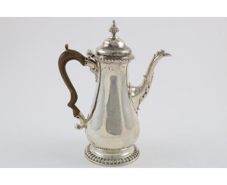 A GEORGE III COFFEE POT. of baluster form, with a domed cover, domed foot, gadrooned borders and a leaf-wrapped spout, creste