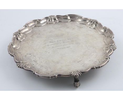 A LATE GEORGE V SALVER. of shaped circular outline, with a moulded shell and scroll border, the centre with a presentation in