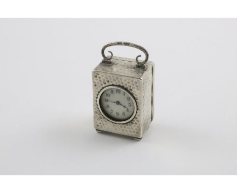 AN EDWARDIAN CARRIAGE TIMEPIECE. on button feet, with a hammered finish and a swing finial, gilt interior, initialled, by Gol