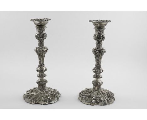 A PAIR OF VICTORIAN CANDLESTICKS. in the Rococo manner, with foliate scroll decoration and detachable nozzles on raised, shap