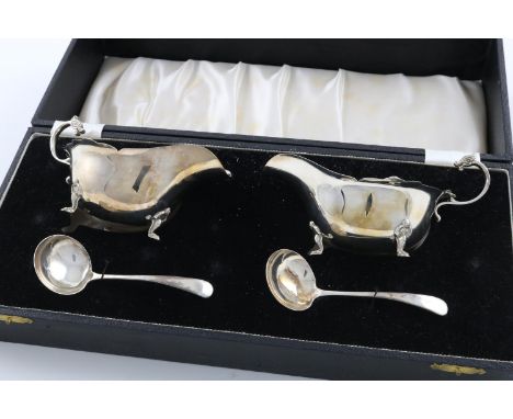 AN ELIZABETH II CASED PAIR OF SAUCE BOATS AND MATCHING LADLES. with wavy rims and mythical creature scroll handles, contained
