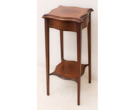 An Edwardian satinwood-banded mahogany serpentine lamp table - the moulded top raised on square tapered supports united by a 