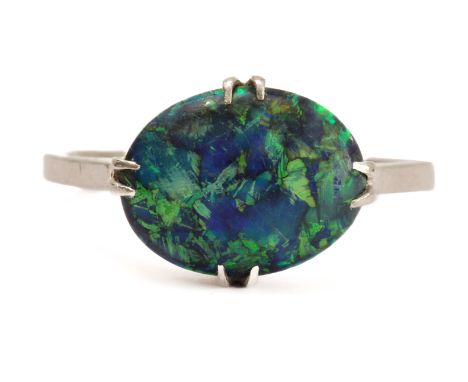 A mid-century platinum and black opal doublet ring - 1920s-30s, the 1.3 x 1 cm. oval cabochon opal in a four claw setting, ma