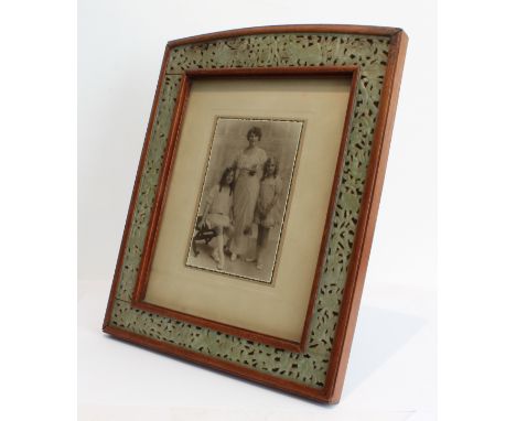 A large early 20th century mahogany photograph frame: with arched top and hand-carved and pierced celadon jade border depicti