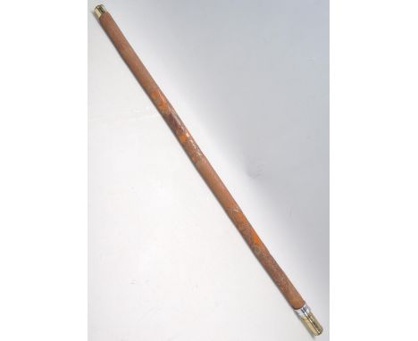 A heavily carved sword stick / walking stick decorated with a carved monkey with floral and pattern decoration. Brass knop an