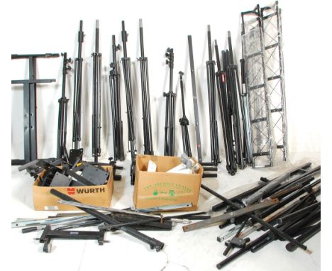 A large group of multiple pairs and single speaker stands and microphone stands with most being adjustable raised on tripod b