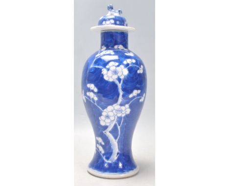 A late 19th Century Chinese blue and white baluster vase hand painted in the prunus pattern, having a lid with a fu dog finia