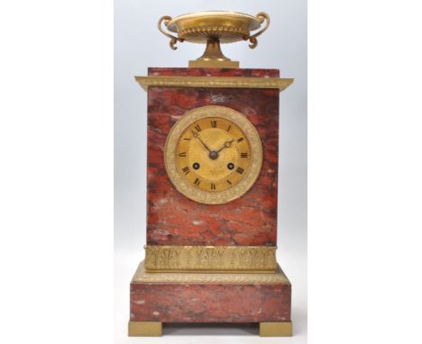 An early 20th Century red marble mantel clock of upright rectangular form having a brass urn atop with brass acanthus leaf ba