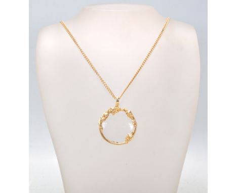 A yelllow metal 20th century large puzzler - magnifying glass pendant on langard necklace chain. The puzzler with rococo&nbsp