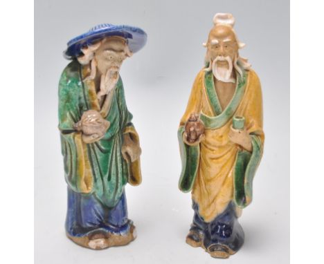 A pair of 1920's Chinese export Ming Dynasty style ceramic figurines in the form of two men glazed in yellow blue and green, 