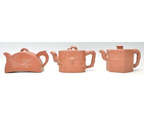 A collection of 3 20th Century Chinese Yixing red clay teapots of squat form having&nbsp; short spouts and finial lids. To in