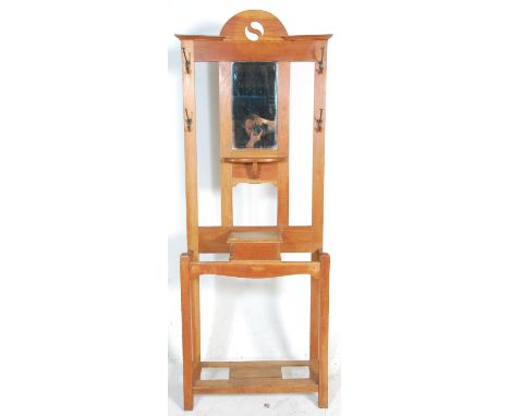 A 20th Century oak framed hall stand having a central rectangular bevelled mirror flanked by two pierced panels with four coa