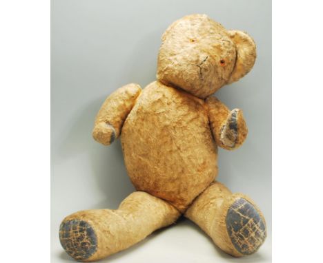 A vintage early to mid 20th Century childs teddy bear constructed from mohair with leather patches to the paws and feet.