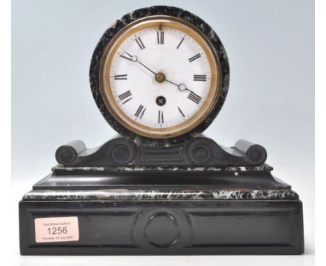 A late 19th Century black marble barrel mantel clock having a plinth base with round clock mounted to the top flanked by scro