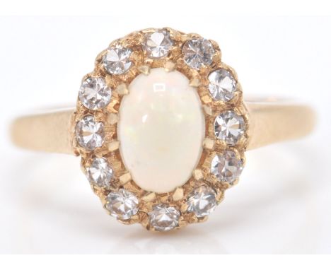 A 9ct gold Birmingham hallmarked opal and white stone ring. The cabochon opal within a halo of white stones. Total weight 2.2