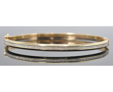 A hallmarked 9ct white and yellow gold and bracelet / bangle. The bracelet having white gold textured diamond cut channel wit