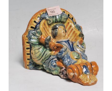 A 20th Century continental faience ceramic wall mounted shelf / sconce having a semicircular shelf to the top with scrolled l