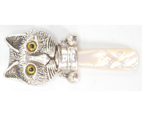 A stamped sterling silver childs rattle in the form of a Louis Wain style cat with yellow glass eyes and a mother of pearl ha