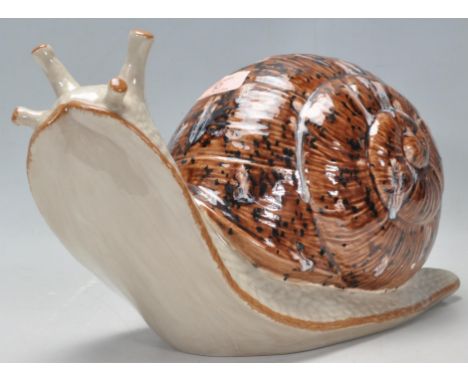A vintage late 20th Century studio art pottery figurine in the form of a snail having a mottled brown glazed shell. Signed to