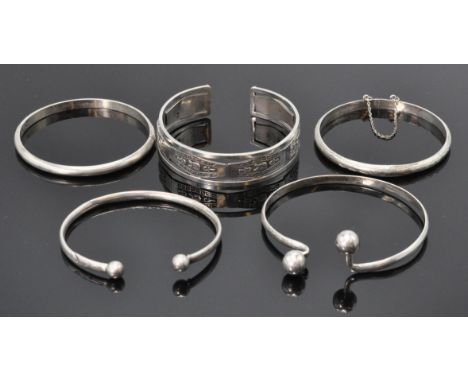 A good group of five silver bangle bracelets to include a Egyptian bangle having engraved panels with central Pharaoh head de