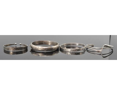 A group of four silver bangle bracelets to include a 1966 Birmingham hallmarked bangle having a push button clasp with engrav