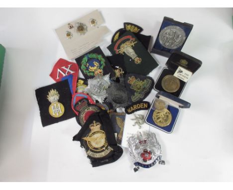 Large collection of military cap badges, buttons, pins, and patches including an RAF Middle Eastern Air Force patch, a Royal 